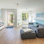 Wohnzimmer mit grauem Sofa, Fernseher und Blick auf Garten.
