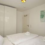 Schlafzimmer mit weißem Bett, Kleiderschrank und Wandbild.