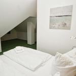 Schlafzimmer mit Dachschräge, Bett, Wandbild und Nachttischlampe.