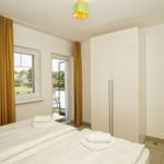Bedroom with bed, white curtains, and view of the garden.