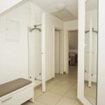 Hallway with closet, bench, and view into living area.