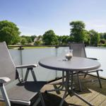 Terrace with table and two chairs, view of green trees and houses.