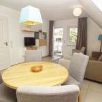 Living and dining area with round table, sofa, and TV. Balcony via sliding door.