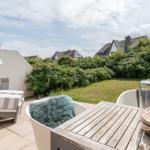 Terrace with table, chairs, and view of garden and houses.