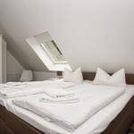 Bedroom with sloped ceiling, skylight, and bed with white bedding.