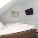 Bedroom with sloped ceiling, bed, TV, and door