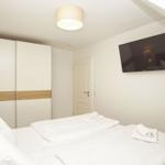 Schlafzimmer mit Doppelbett, Schrank und Wandfernseher.