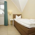 Ein Schlafzimmer mit Bett, Nachttisch und Fenster mit Vorhang.