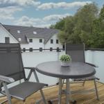 Terrasse mit Tisch und zwei Stühlen. Hintergrund: weißes Haus und Bäume.