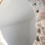 Spiegel mit Mosaikrahmen aus Muscheln und Steinen an Wand