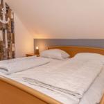 Schlafzimmer mit Doppelbett, Holzkommode und Wand mit Ankermotiv.