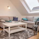 Wohnzimmer mit zwei Sofas, Couchtisch und Dachfenster. Bücherregal und Sessel sind vorhanden.