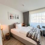 Schlafzimmer mit Bett, Wandbild und Fenster mit Vorhängen.