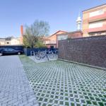 Hinterhof mit Fahrradständer, gepflastertem Bereich und Mauer. Ein Auto parkt daneben.