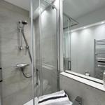 Dusche mit Glaswand, Spiegel und Handtuch auf Waschbecken