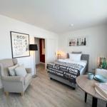 Schlafzimmer mit Bett, Sessel und Tisch. Wandbilder und Holzboden.