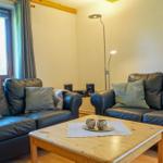 Two leather sofas, wooden table, window with curtains, floor lamp, and wall picture.