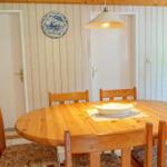 Round wooden table with chairs and a bowl. A blue plate hangs on the wall.