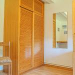 Bedroom with wooden bunk bed, wardrobe, and mirror on the wall.