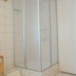 Bath with shower, wooden shelf, and white door
