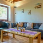 Wohnzimmer mit Ledersofa, Holztisch und Fenster mit Blick nach draußen.