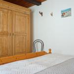 Schlafzimmer mit Holzschrank, Bett und Wandbildern.