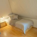Schlafzimmer mit Bett, Kinderbett, Stuhl und Nachttisch unter schrägem Dach