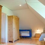 Schlafzimmer mit Holzmöbeln, Babybett und Dachschräge