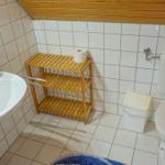 Badezimmer mit Toilette, Waschbecken und Holzregal.