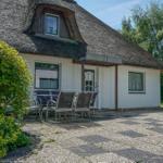 Haus mit Strohdach, weißer Fassade und Gartenbereich mit Sitzgelegenheit.