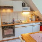Kitchen with wooden countertop, white cabinets, and built-in oven. Dining table with tablecloth.
