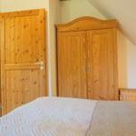 Bedroom with wooden wardrobe, bed, and door to hallway. Sloped ceiling on wall.