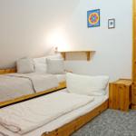 Room with two beds, wooden furniture, and wall pictures.