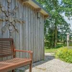 Wooden bench in front of a wooden shed with wood decor. Garden with chairs and flowers.