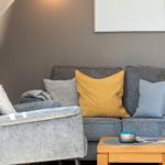 Ein grauer Sofa mit Kissen und einem Holztisch im Wohnbereich.