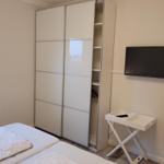 Schlafzimmer mit Doppelbett, Schwebetüren-Schrank und Wand-TV.