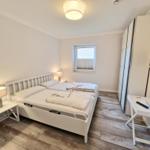 Schlafzimmer mit Bett, Nachttischen, Schrank und Fernseher an der Wand.