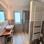 Badezimmer mit Waschbecken, Dusche und Heizkörper