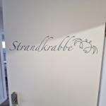 Türe mit Aufschrift Strandkrabbe und Krabbenmotiv.