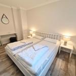 Schlafzimmer mit Doppelbett, zwei Nachttischen und einem Spiegel an der Wand.