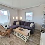 Wohnzimmer mit L-förmigem Sofa, Esstisch und dekorativen Elementen.