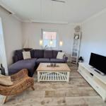 Wohnzimmer mit Ecksofa, TV-Bodenregal und Holztisch.