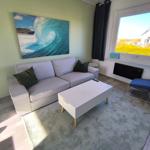 Wohnzimmer mit Sofa, Couchtisch und Wandbild. Fensterblick auf Garten.