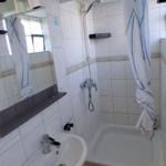 Badezimmer mit Dusche, Waschbecken und Spiegel