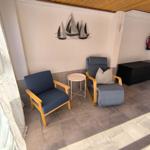 Zwei Sessel und ein kleiner Tisch stehen auf einer Terrasse mit Wanddekoration.