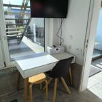 Arbeitsplatz mit Tisch, Stuhl und Fernseher. Blick auf Balkon.