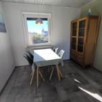 Esszimmer mit Tisch, Stühlen, Schrank und Fenster. Holzfußboden und Wandbild.