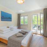 Schlafzimmer mit Doppelbett, TV und Balkon. Wandbild und Holzmöbel.