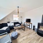 Wohnzimmer mit Sofa, Kamin, TV und Holzboden