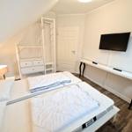 Schlafzimmer mit Doppelbett, Kleiderschrank, Schreibtisch und Wand-TV.